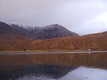 Scenic view of lake by mountains against sky