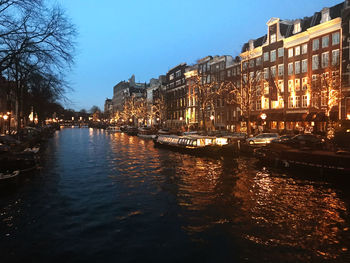 Canal amidst illuminated buildings in city at night