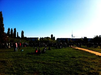 People on grassy field against clear sky
