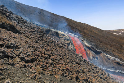 Colata di lava incandescente sul vulcano etna ,sicilia , con fumo e canale di scorrimento lavico