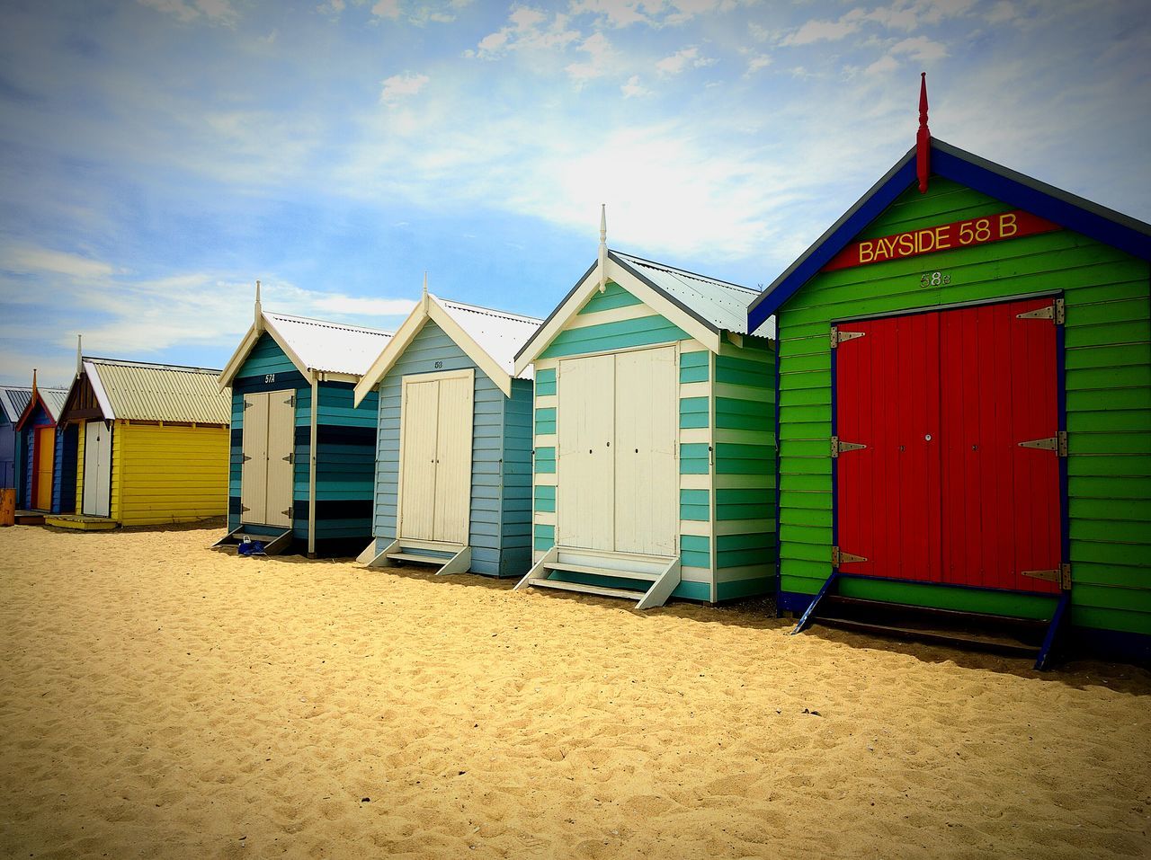 building exterior, architecture, built structure, sky, cloud - sky, house, multi colored, cloud, sand, beach, beach hut, in a row, day, outdoors, cloudy, blue, residential structure, no people, window, facade