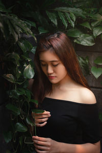 Young woman looking away while plants