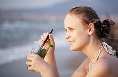 Close-up of beautiful woman having mojito at beach