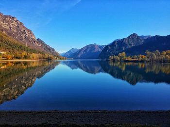 Scenic view of lake and mountains against blue sky