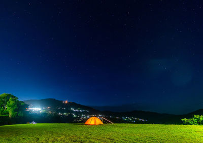 Illuminated field against sky at night