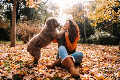 Full length of a young woman sitting on autumn leaves