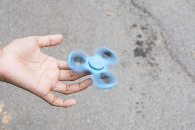 Cropped hand spinning fidget spinner on road