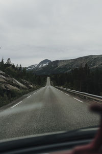 Road seen through car windshield against sky