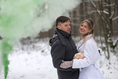 Portrait of smiling bride with groom during winter