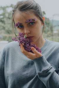 Portrait of a young woman holding lilac flowers plant