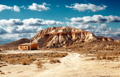 Sunset desert landscape with house and mountain