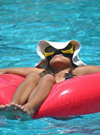 Girl relaxing on red inflatable ring in sea