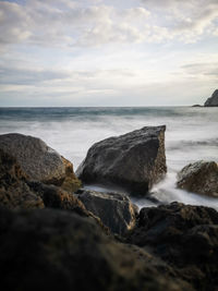 Scenic view of rocks in sea against sky