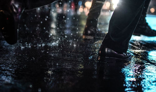 Low section of man standing on wet glass