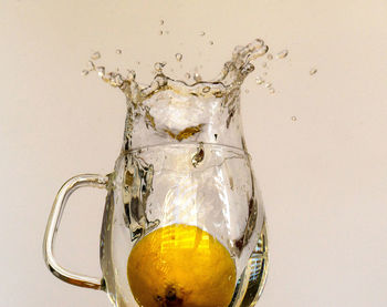 Close-up of water splashing on glass against white background