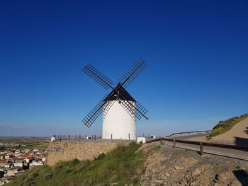 Traditional windmill on landscape against clear blue sky