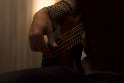 Cropped image of person playing guitar at home