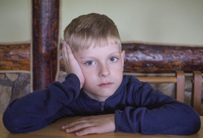 Portrait of sad boy sitting on chair at home