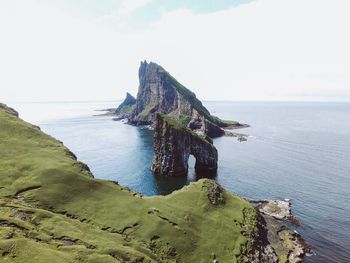 Scenic view of sea by cliff against sky