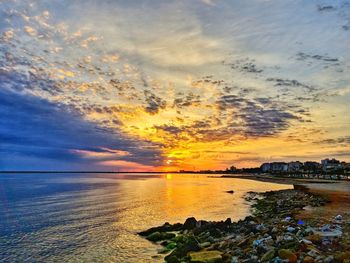 Scenic view of sea against dramatic sky during sunset