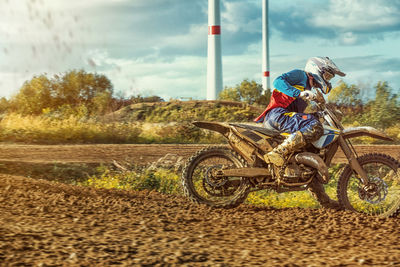 Man riding motorcycle on field against sky