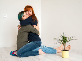 Portrait of woman embracing girlfriend kneeling at home