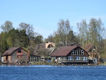 Houses by river and buildings against sky