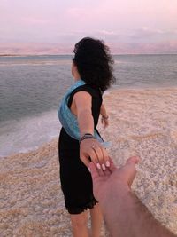 Cropped image of boyfriend holding girlfriend hand at beach