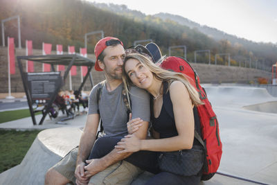 Man sitting with woman on concrete wall at skatepark