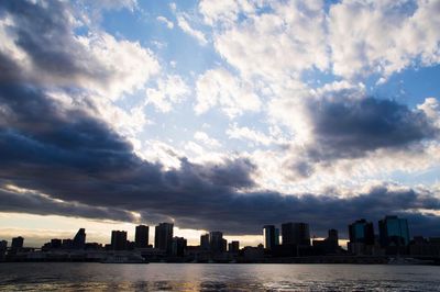 Sea and buildings against sky during sunset