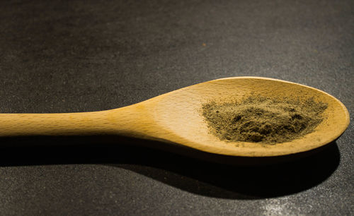 Close-up of ground spice in wooden spoon on table