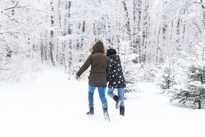 Rear view of woman walking on snow covered land