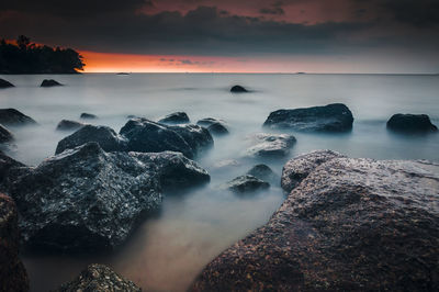 Rocks in sea at sunset