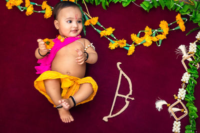 Cute indian boy dresses as lord rama with bow and flowers from top angle