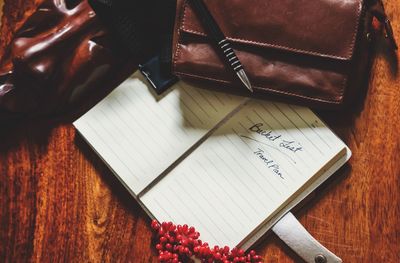 High angle view of book by pen and purse on wooden table