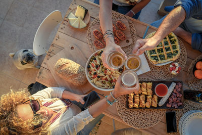 High angle view of friends toasting drinks while having food at table