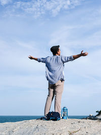 Rear view of man standing by sea against sky