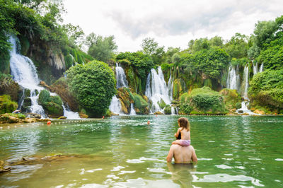 Rear view of father and daughter in river