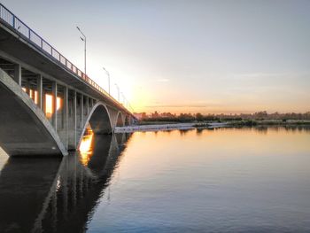 Bridge over river against sky during sunset