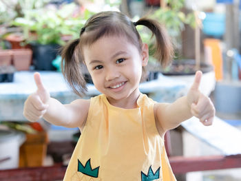 Positive charming 4 years old cute baby asian girl, little child with adorable pigtails hair smiling