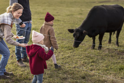 Girls with parents feeding animals in farm