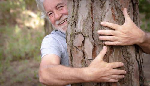Midsection of man holding tree trunk