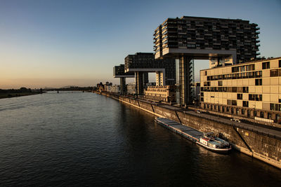 River in city against clear sky during sunset
