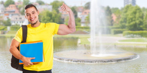 Portrait of young man holding yellow while standing against blurred background