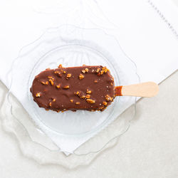 Chocolate peanut ice cream bar in pretty transparent dish set with white embroidered serviette 