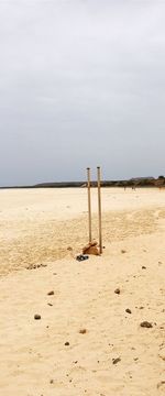 Wooden posts on beach against sky