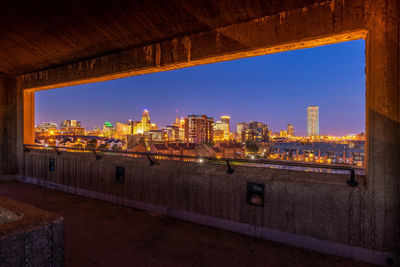 Illuminated cityscape against sky seen through window