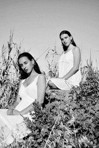 Portrait of happy young women sitting on sand at beach