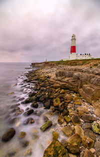 Lighthouse by sea against sky