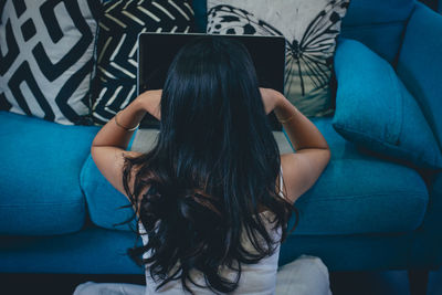 Rear view of woman sitting on sofa at home